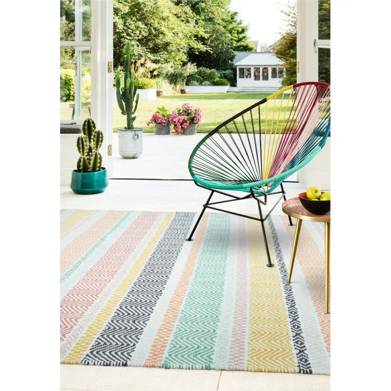 Striped multicolour rug in bright room with modern accent chair and potted cacti