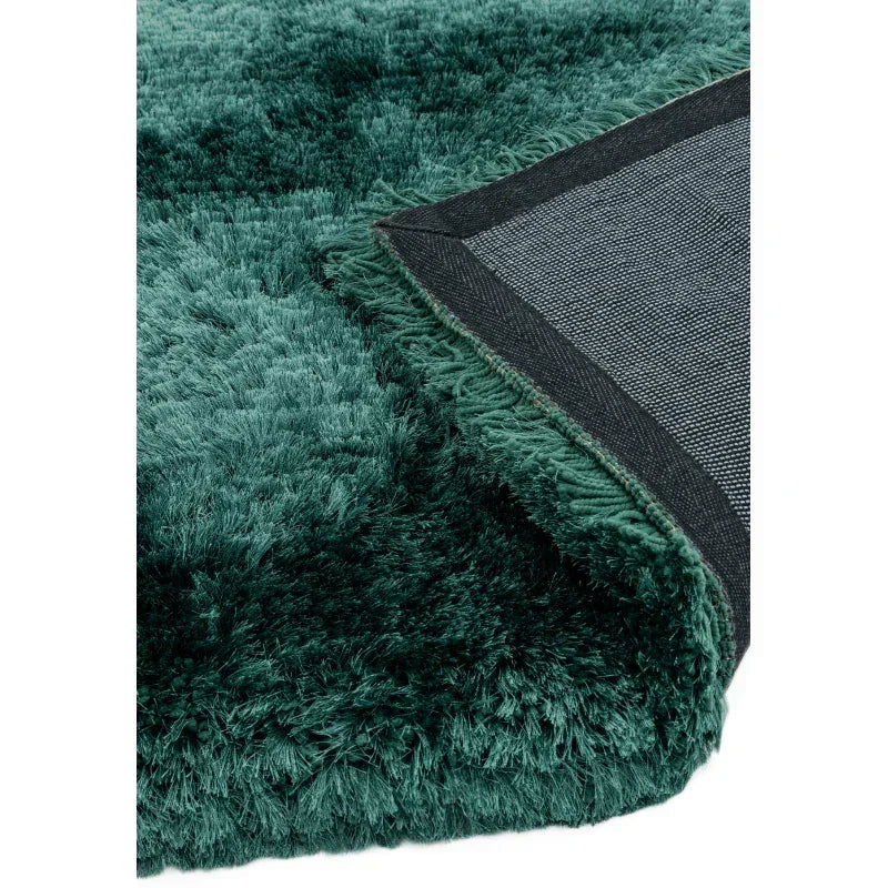 Close view of green shaggy rug with textured pile and black non-slip backing