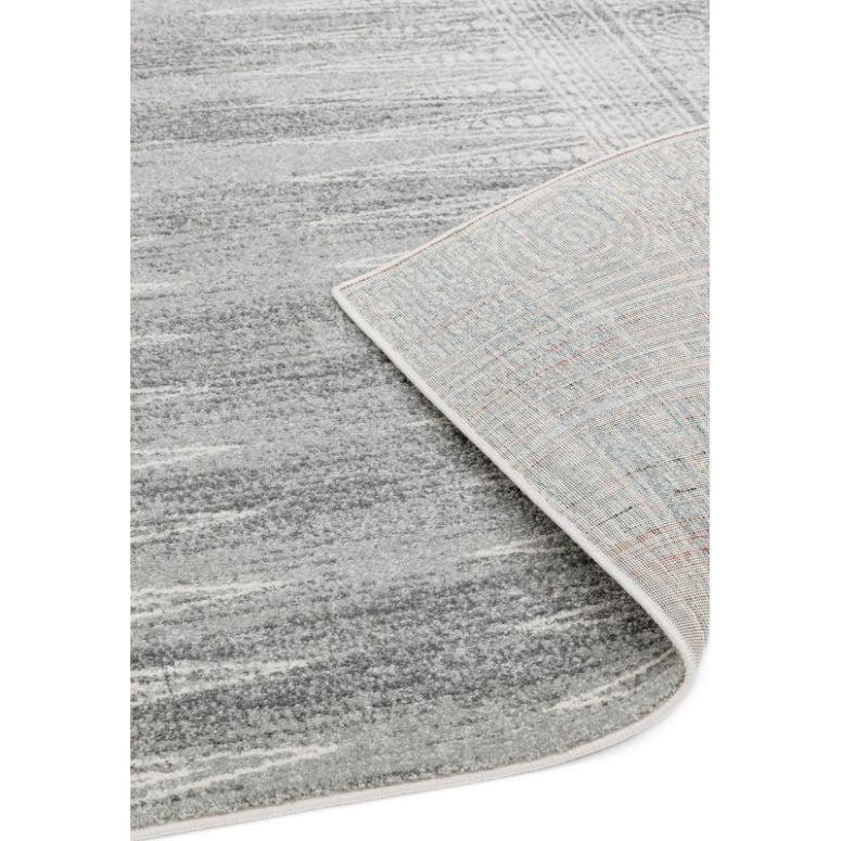 Grey area rug with subtle pattern, one corner flipped to show backing detail