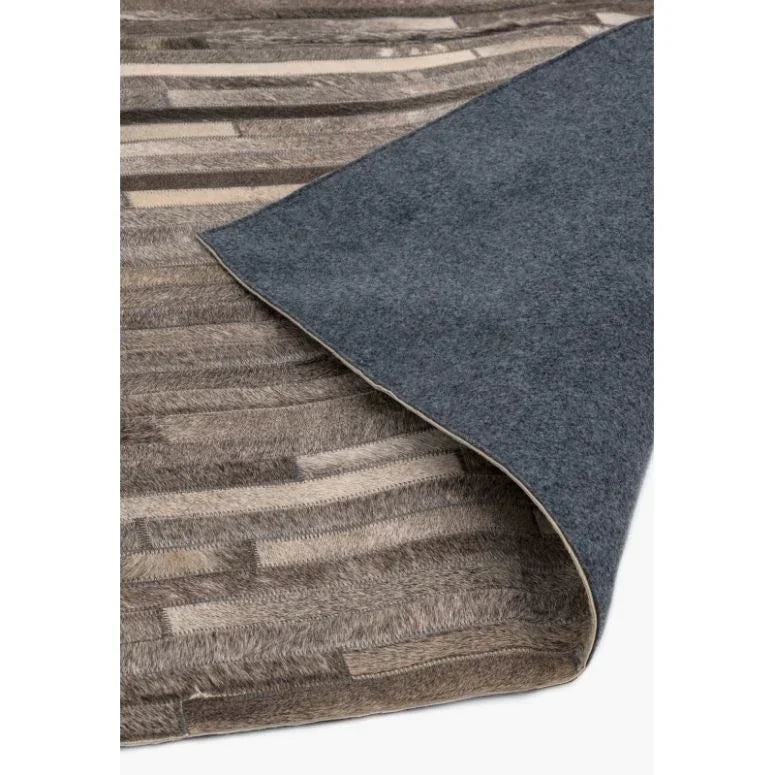 Beige and brown patchwork area rug with grey felt backing corner folded over