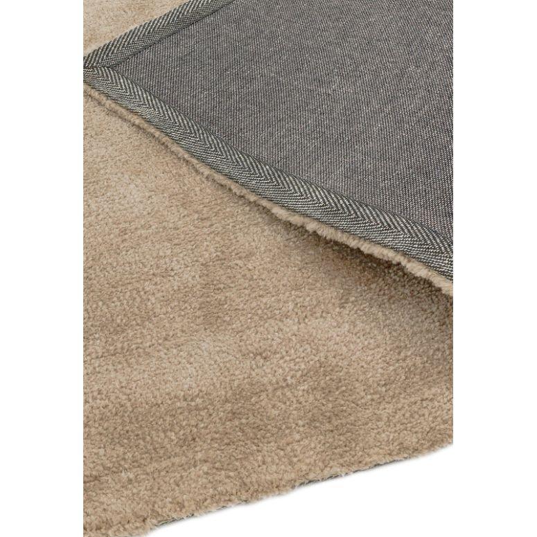 Close-up of beige shaggy rug with textured pile and contrasting grey fabric backing