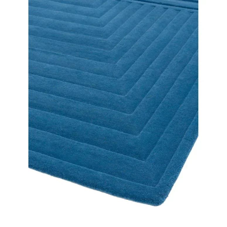 Blue wool rug with geometric pattern, close-up of soft textured surface and corner detail