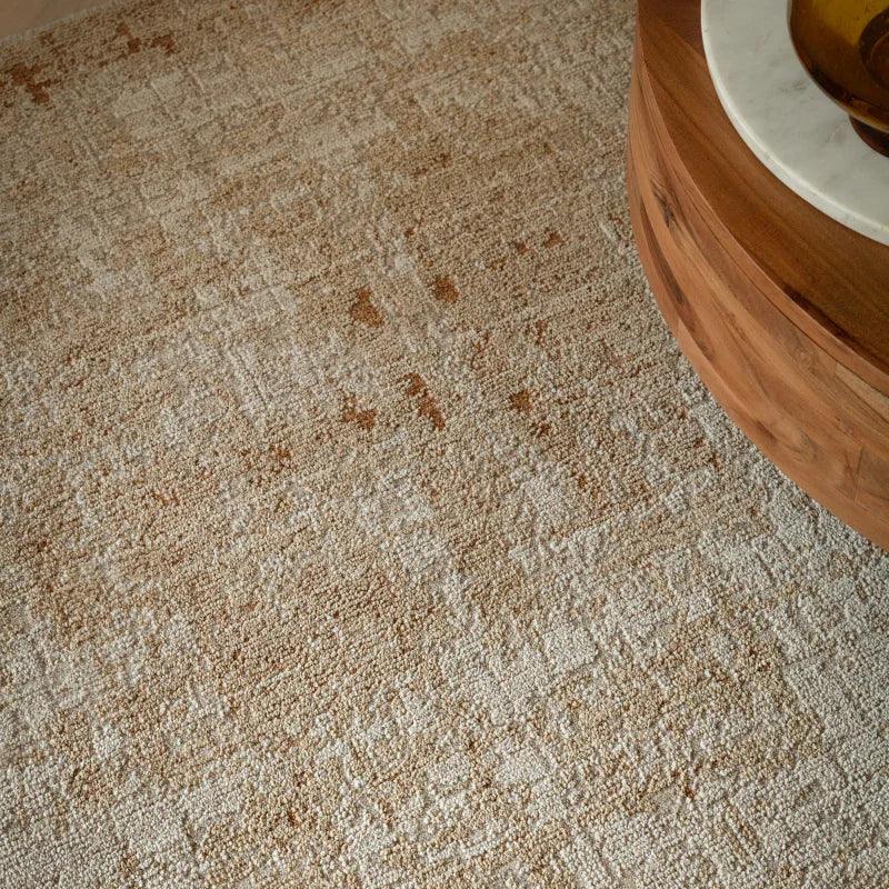Beige textured living room rug beside round wooden coffee table with marble top