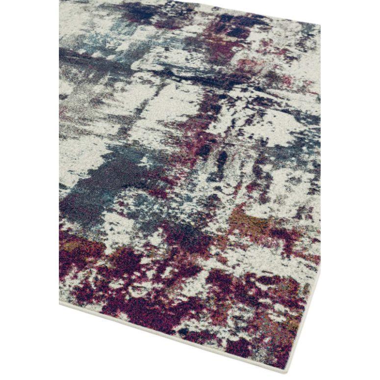 Abstract patterned area rug with cream, blue, and burgundy tones, corner view