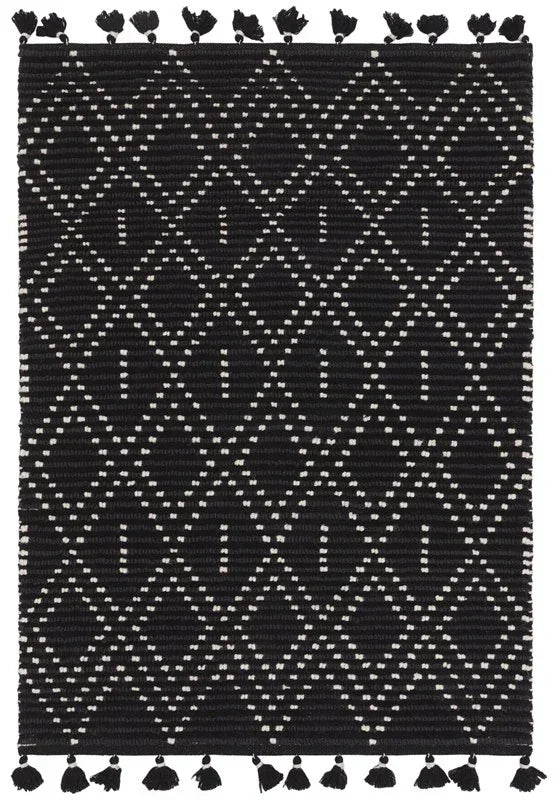 Black geometric patterned area rug with white diamond design and tassels on edges