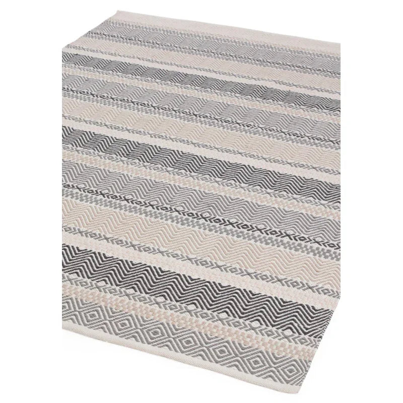 Geometric patterned area rug in grey and cream with textured zigzag and diamond stripes