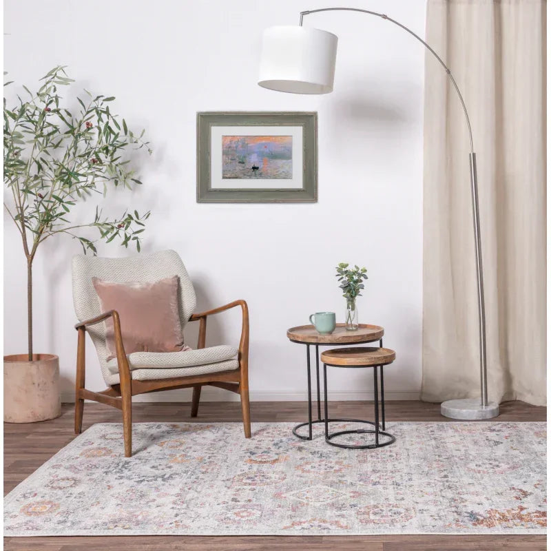 Mid-century armchair with cushion, nested side tables and floor lamp on patterned rug
