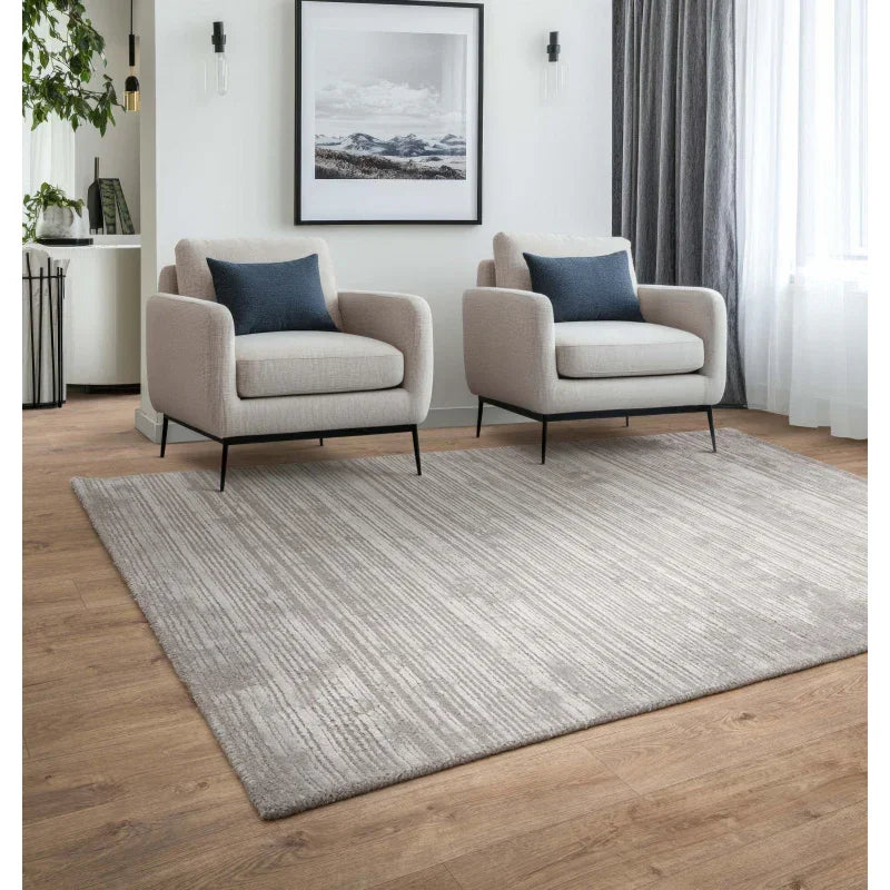 Modern living room with two beige armchairs and a large grey area rug on wood flooring