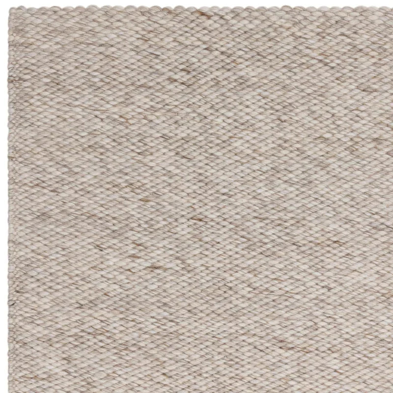 Close-up of beige woven rug texture with subtle flecks, showing detailed weave pattern