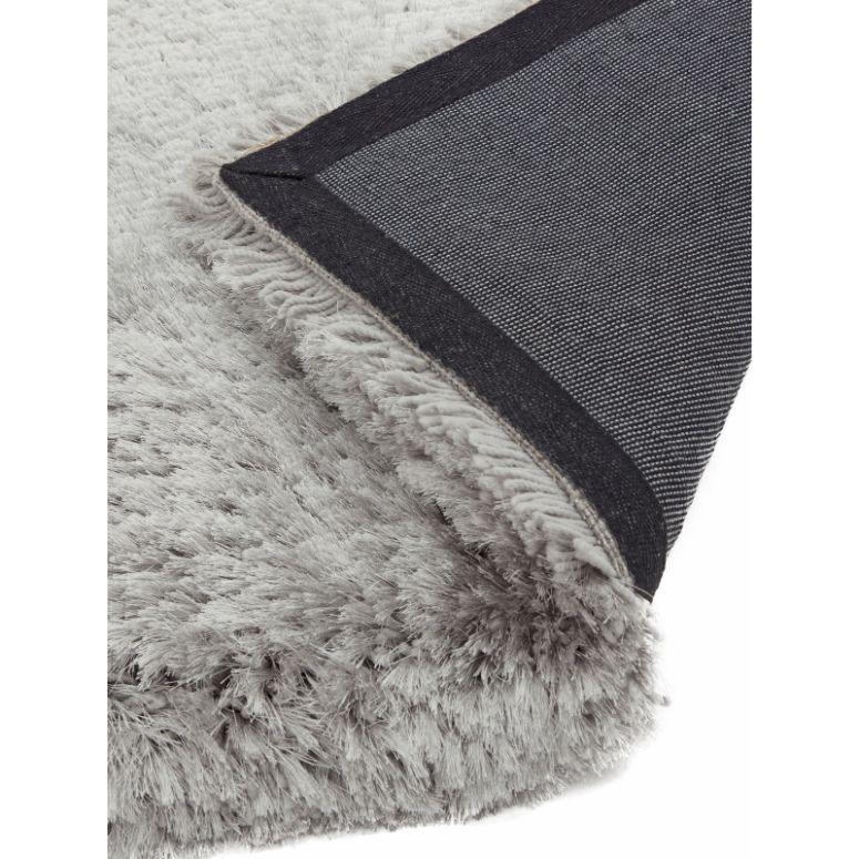 Close up of grey shaggy rug with textured pile and corner showing backing detail
