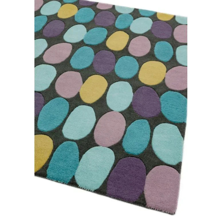 Modern area rug with multicolored oval patterns on a dark background, corner view
