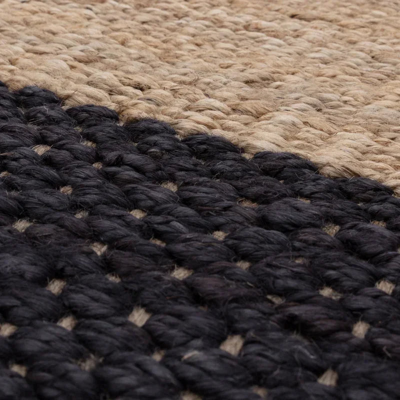 Closeup of woven jute rug with natural and black fibers in a textured pattern