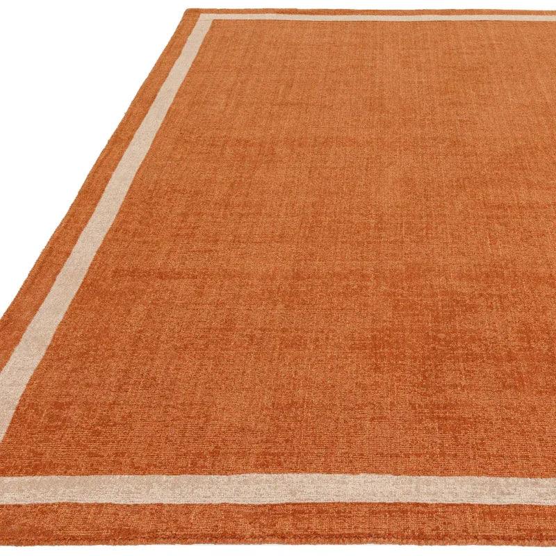 Burnt orange area rug with beige border and textured finish
