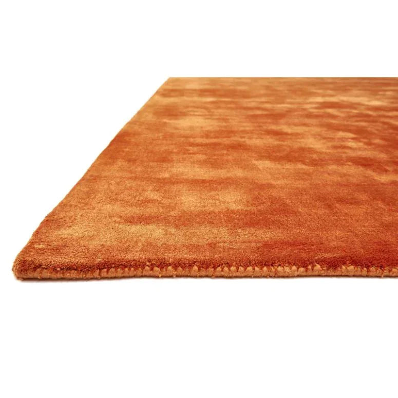 Close-up of orange area rug with soft texture and finished edge