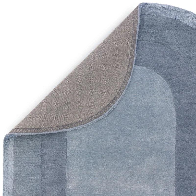 Corner of blue gradient area rug with grey backing folded over