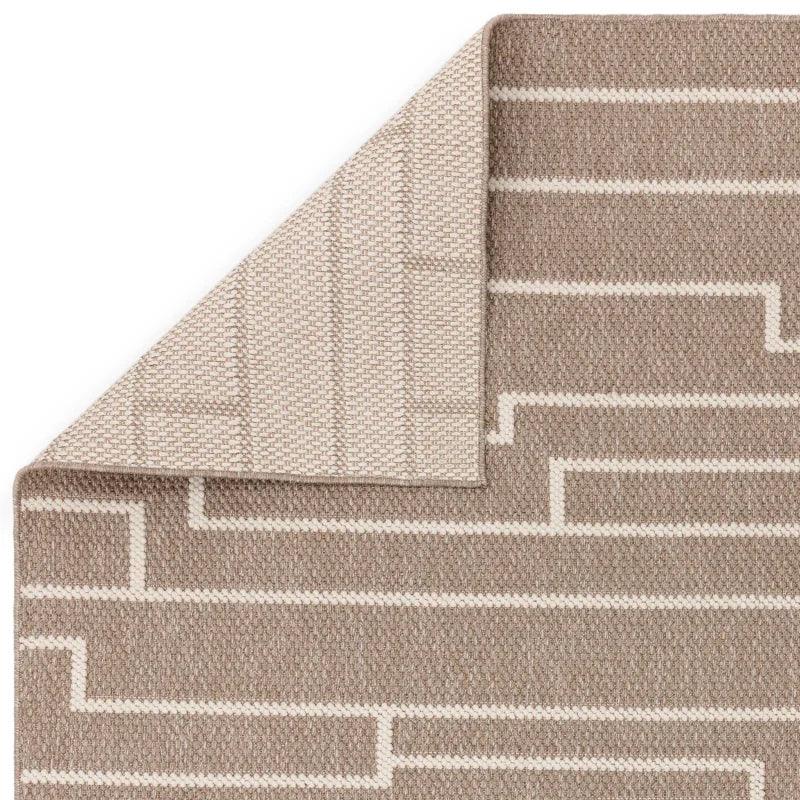 Beige and cream woven rug with geometric line pattern and folded corner showing reverse side
