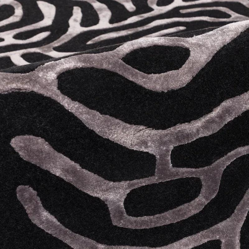 Close-up of black and grey patterned rug with raised abstract design