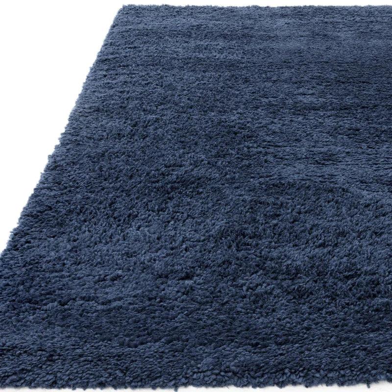 Navy blue shaggy rug with thick pile texture, corner view shown on white background