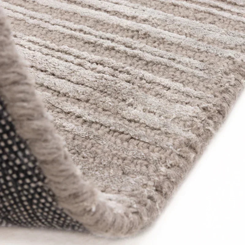 Close-up of light grey textured rug with subtle stripe pattern and soft pile