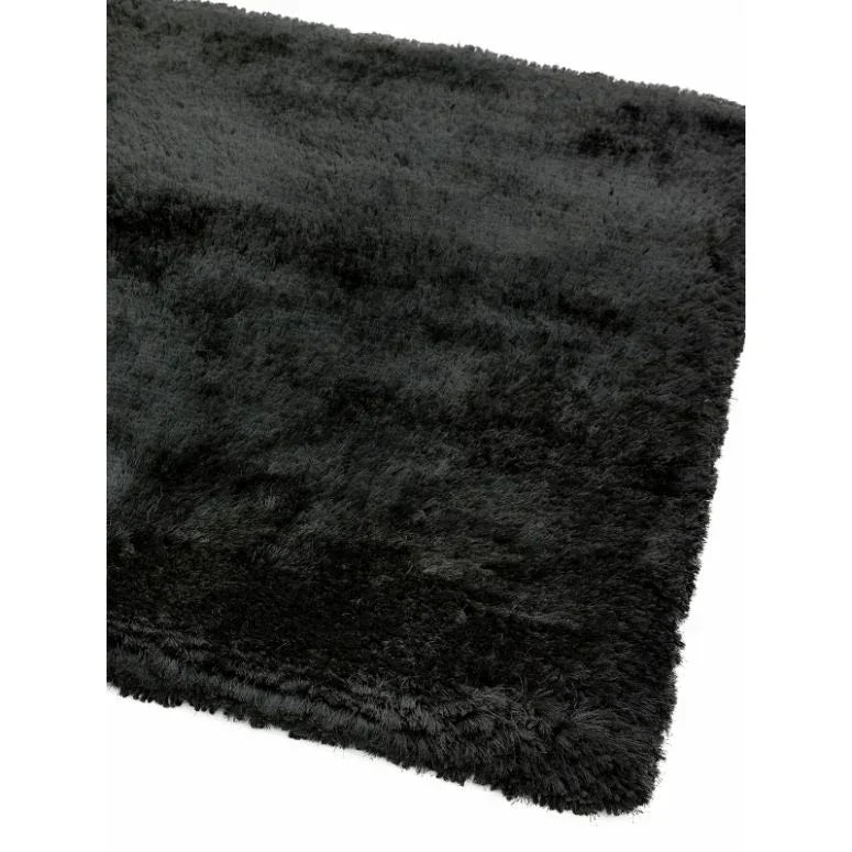 Black fluffy rug with soft pile and finished edge, shown from a corner angle