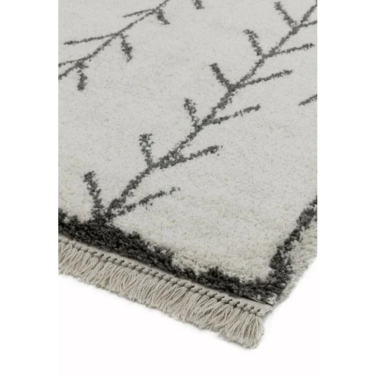 cream area rug with black geometric branches and fringe detail on one corner