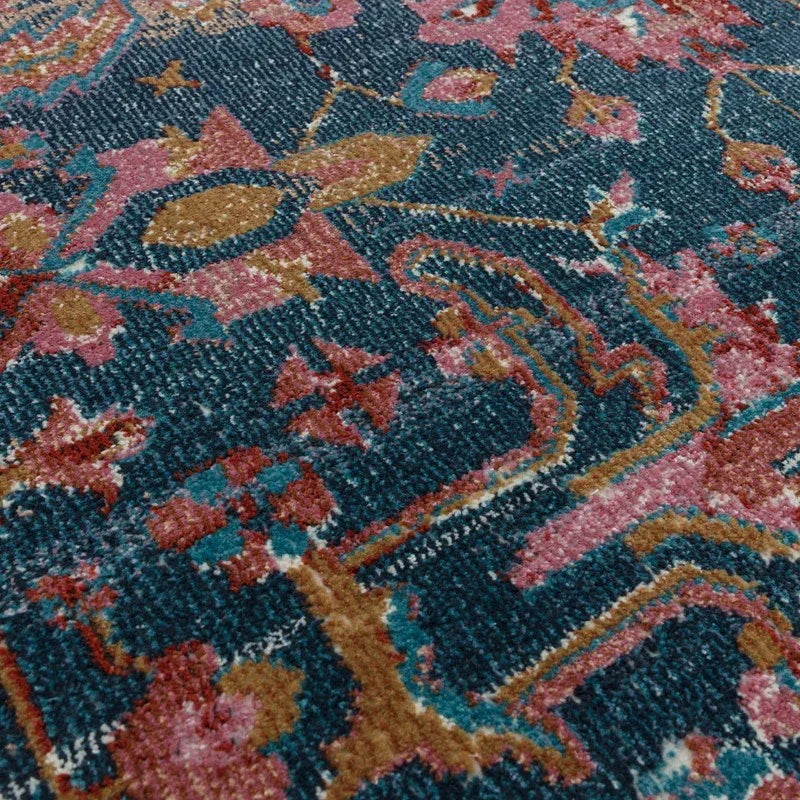 Closeup of patterned area rug with blue, pink, and mustard detail and soft texture