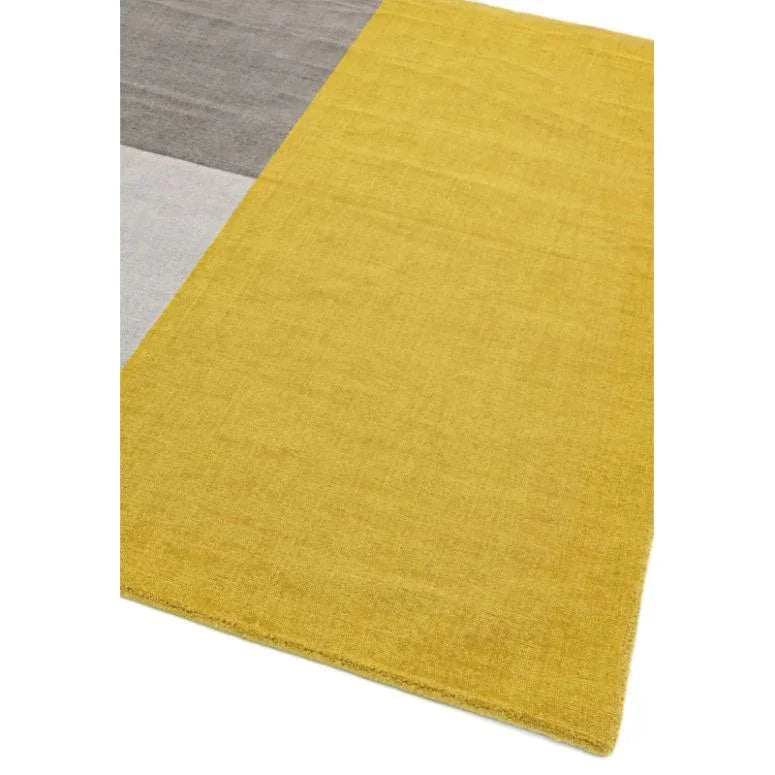 Modern area rug with yellow, grey, and beige color blocks, corner view