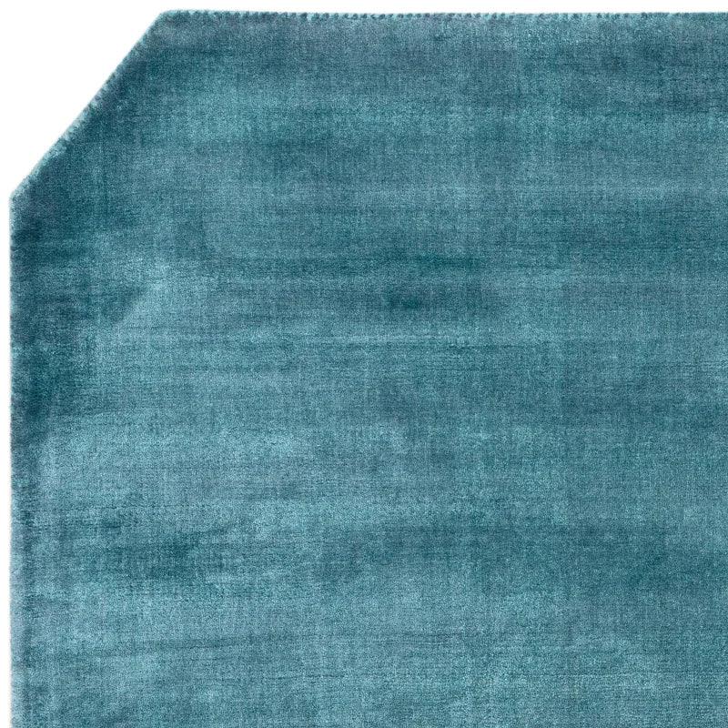 Teal area rug with soft texture and distinctive angled corner detail