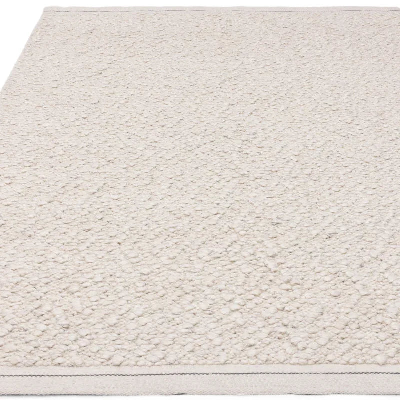 Ivory textured wool rug with looped pile and stitched edge detailing