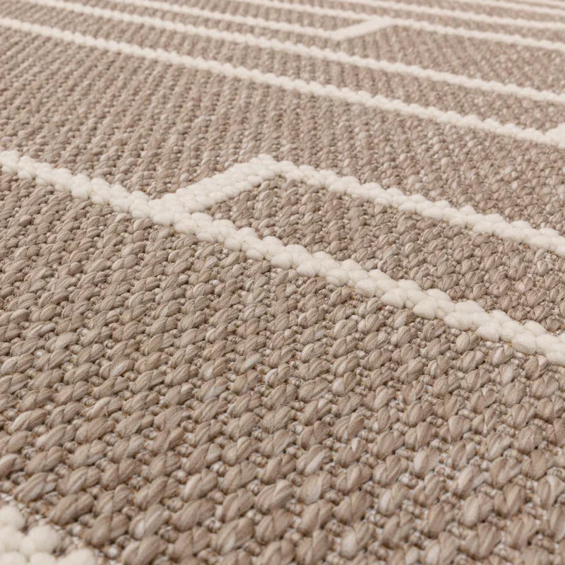 Beige woven rug with white geometric lines and textured surface, close-up angle