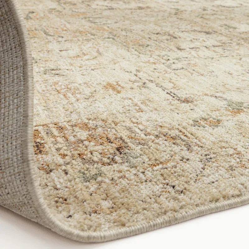 Beige patterned area rug with textured pile and detailed edge on light floor