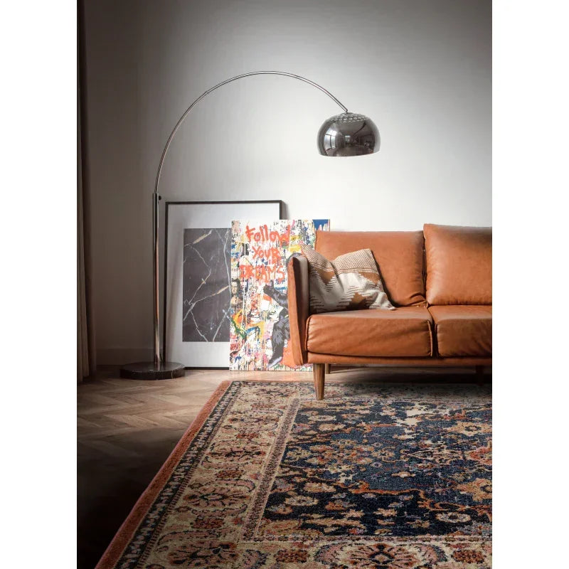 Tan leather sofa with patterned cushion, vintage rug and modern arc floor lamp in living room
