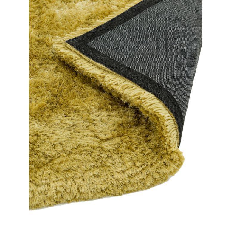 Close-up of gold shaggy rug with corner flipped to show backing