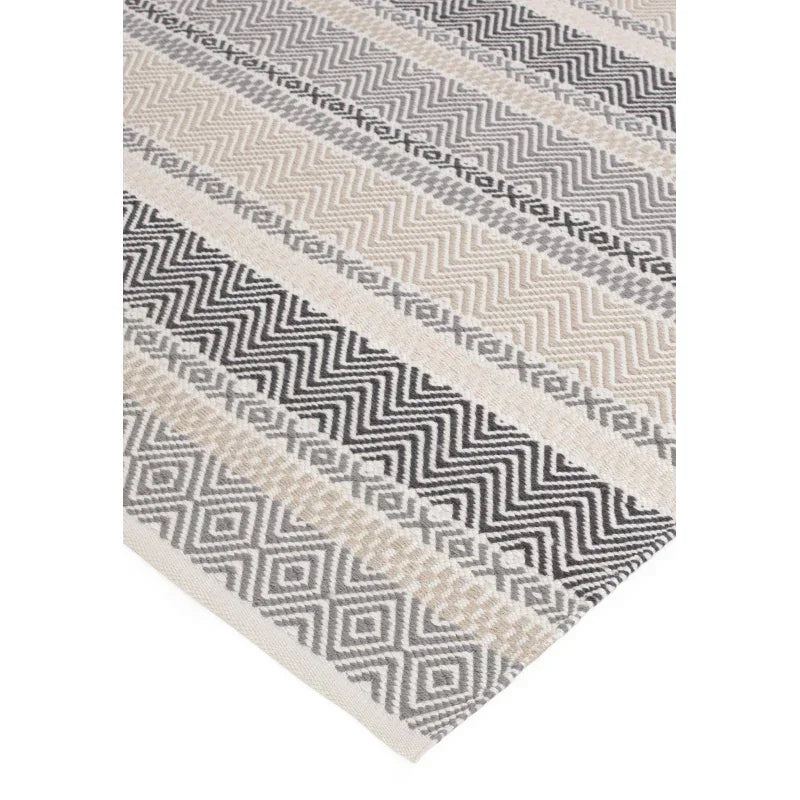 Geometric patterned rug in black, grey, and beige with diamond and zigzag designs