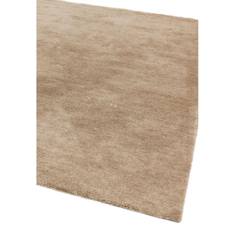 Beige area rug with soft pile and textured finish, shown from angled corner view