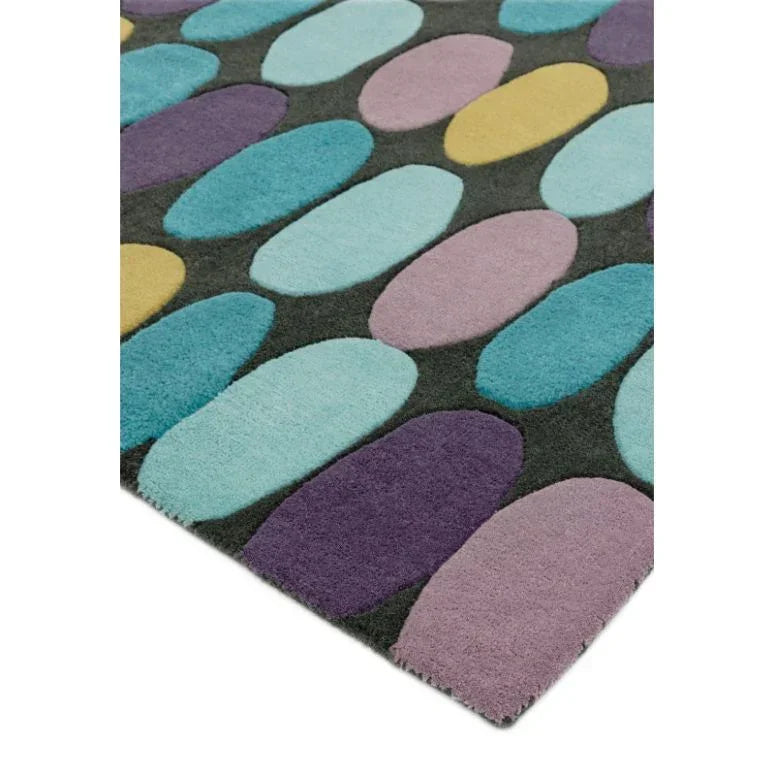Modern area rug with multicoloured oval patterns on a dark background, angled view