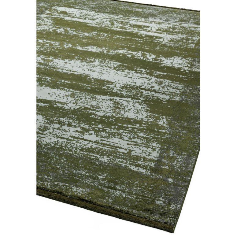 Green area rug with distressed abstract pattern and subtle textured finish, corner view