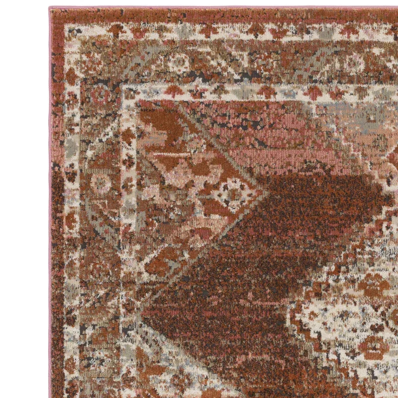 Corner of red and cream patterned area rug with distressed vintage design
