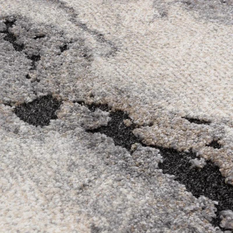 Close up of modern area rug with grey and cream abstract pattern and textured pile