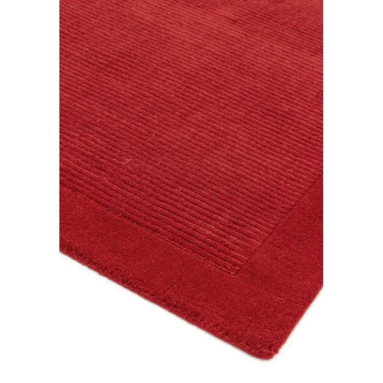 Red textured area rug with subtle border, close-up of corner and ribbed pattern
