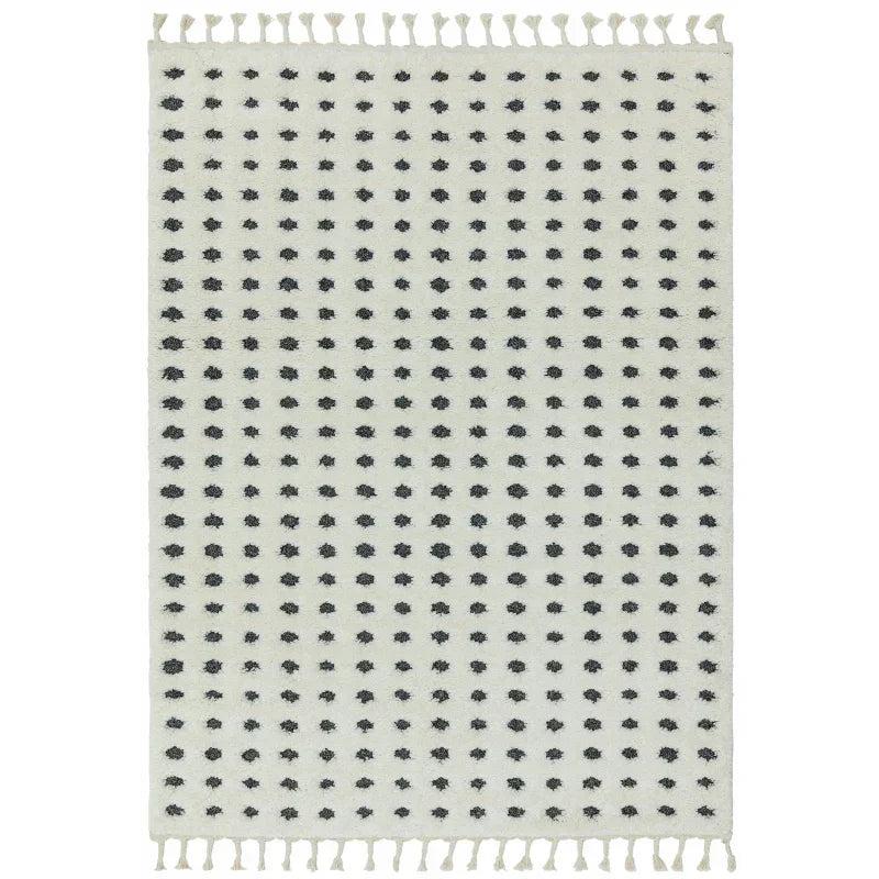 Cream area rug with black dot pattern and tassel fringe edges
