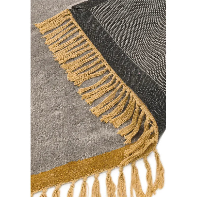 Grey and mustard fringed rug with woven texture and decorative tassels on corner