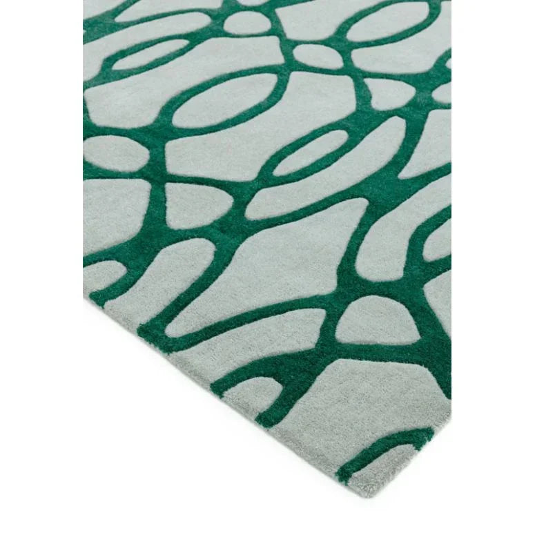 Modern area rug with green abstract pattern on light grey background, corner close-up