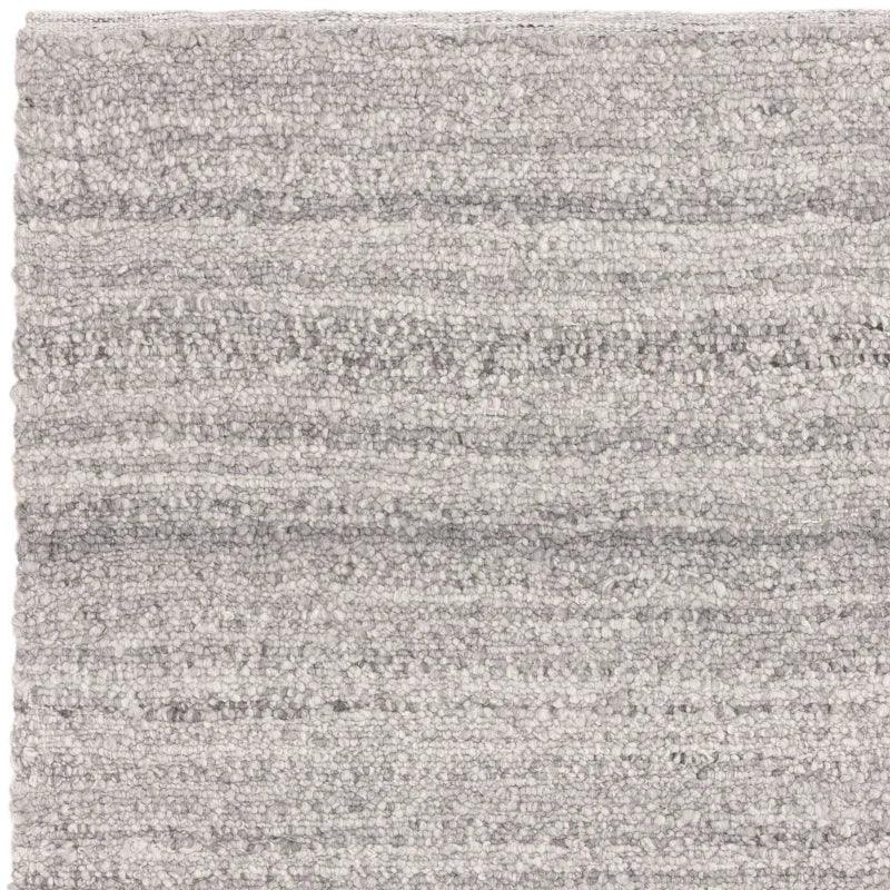 Close up of textured grey wool rug with looped pile and subtle striped pattern