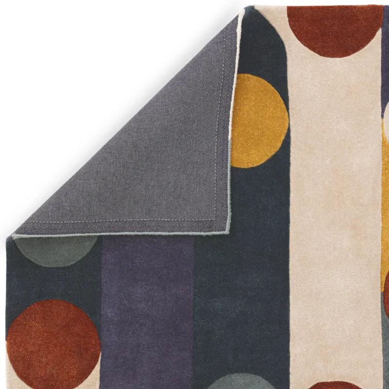 Modern area rug with colorful circles and stripes, corner folded to show backing