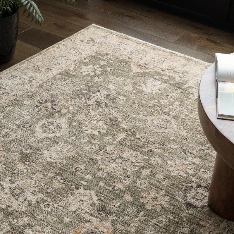 Green patterned area rug on wooden floor beside round coffee table