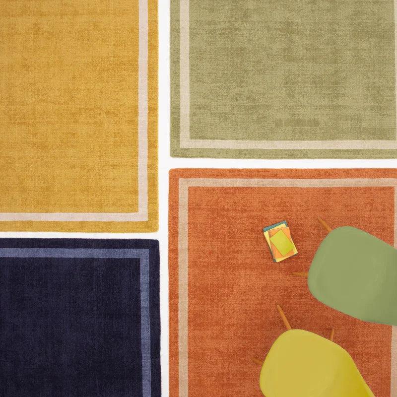 Colorful modern area rugs with geometric borders, yellow chair and stacked books on orange rug