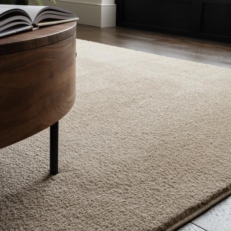 beige living room rug on wooden floor beside round wood coffee table