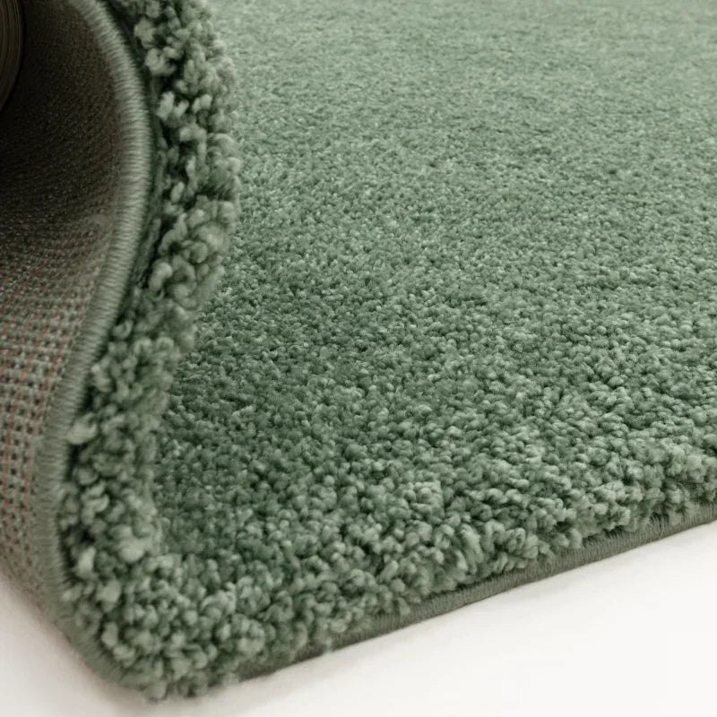Close-up of green plush carpet with soft pile and textured edging