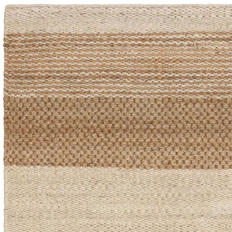 Natural jute rug with woven texture and beige tan color blocks, close-up detail view